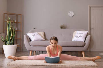 Beautiful young woman reading book while doing leg-split at home
