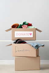 Cardboard boxes with donation clothes on light background - obrazy, fototapety, plakaty