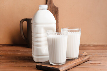 Gallon bottle and glasses of milk on wooden table