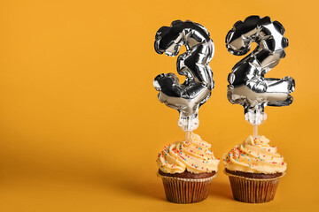 Tasty Birthday cupcakes with number 32 on color background