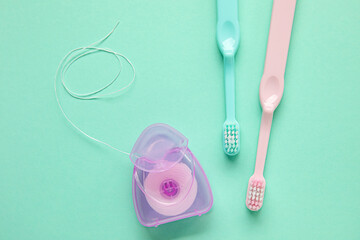 Dental floss and toothbrushes on green background