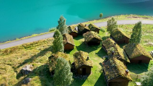 Grass roof house cluster on a meadow near a lake, Aerial view