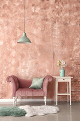 Stylish armchair and vase with flowers on table near pink wall