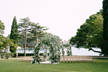 Row of wedding arches surrounded by chairs on a green lawn near the sea