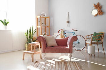 Interior of light living room with pink armchair and modern bicycle