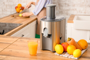Modern juicer with fresh fruits on table in kitchen