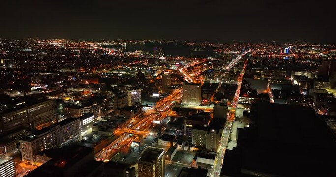 Aerial establishing shot of city at night. Dark sky as traffic flows on highway. Birds eye view.