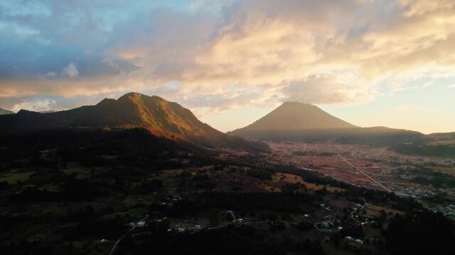 Drone Aerial View Of Cloudy Golden Hour Sunset On Guatemalan Volcanos. Volcan de Carro Quemado and Volcan Santa Maria near Quetzaltenango Xela Guatemala.