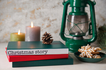 Books with glowing candles, cookies and lantern on grunge background. Christmas story