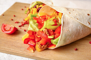 Wooden board of tasty Mexican burritos with vegetables on light background, closeup