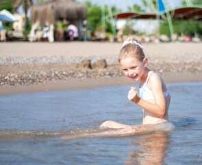 Little girl playing on the beach by the sea