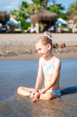 Little girl playing on the beach by the sea