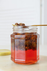 Jar of tasty pine cone jam on light table, closeup