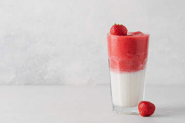 Protein rich smoothies with yogurt and frozen strawberries in glass on light background. Side view of healthy morning berry breakfast