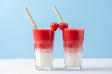 Protein rich smoothies with yogurt and frozen strawberries in glass on light blue background. Concept of drinks for lovers on Valentine's Day. Bright berry as a symbol of the heart