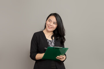 Fototapeta premium Beautiful woman writing on clipboard smiling while looking to left