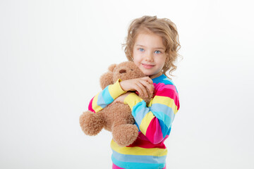 a little cute girl holding a teddy bear isolated on a white background