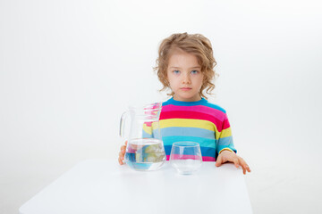 a little cute girl holds a jug of water, pours water into a glass isolated on a white background