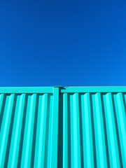 空き地に置かれた青いコンテナと冬の青空