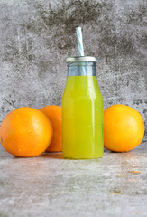 Vertical shot, glass bottle with refreshing orangeade, 
stone base in light colors and copy space.