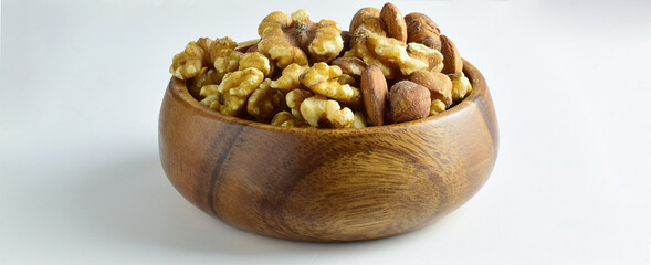 Assortment of dried fruits, hazelnuts, walnuts and almonds in a wooden bowl, light background.