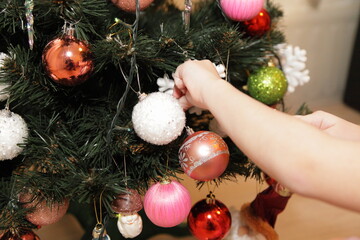 Christmas tree decoration and white children's hands - preparation for xmas