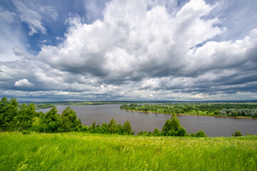 Fototapeta na wymiar Summer landscape, a large full-flowing river, meadow flowers on the banks of the river, mighty clouds in the sky, a tourist walk along the Kama River