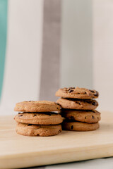 A lot of chocolate chip cookies piled up on a wooden plate.