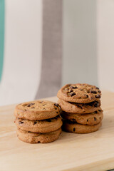 A lot of chocolate chip cookies piled up on a wooden plate.