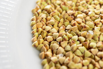Raw green buckwheat in a white plate
