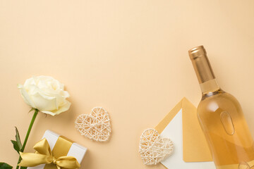 Top view photo of white rose bottle of white wine decorative rattan hearts envelope with paper sheet and white giftbox with gold ribbon bow on isolated beige background with copyspace