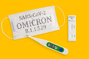 Rapid antigen test kit with positive result during swab COVID 19 testing. Face masks and thermometer isolated on a yellow background