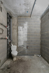 Interior of a new unfinished apartment toilet room made of concrete and foam blocks without...