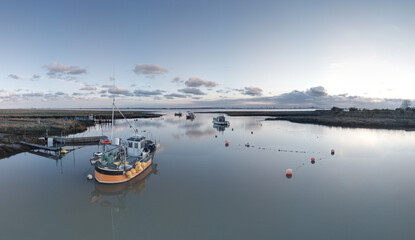 Small fishing boats moored at low tide at Stone Creek inlet, Sunk Island, East Yorkshire, UK