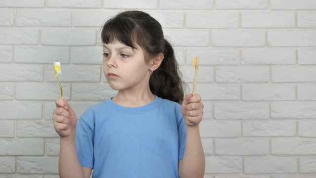Child with two teeth brush. A view of a smiling pretty child with a plastic and orgaic toothbrush in the room.