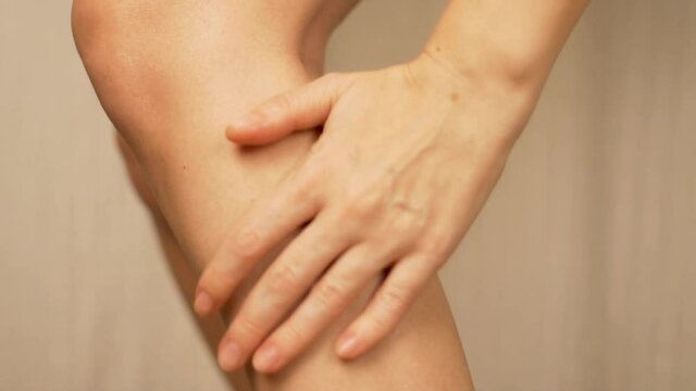 Legs Skin Care. Woman Rubs Cream into Shin and Massages Leg, Close-up.
