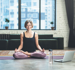 Woman Sitting in Lotus Pose. She is Calm, relaxed and happy outside the window bustling metropolis....