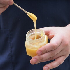 the masseur collects honey from a jar for use in massage