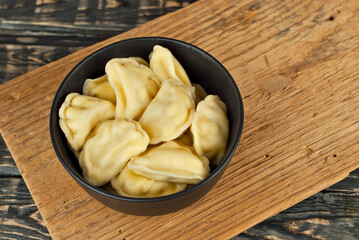 Soldiers in a black bowl. Dough and potato dishes on a black background. Ukrainian national dish on a wooden table. Copy space and free space for text near food.