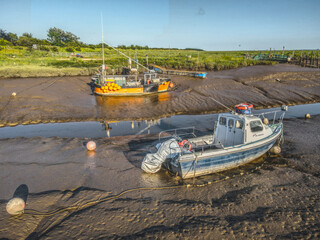 Fototapeta premium Small fishing boats moored in the Stone Creek inlet at Sunk Island, East Yorkshire, UK