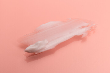 White smear of cosmetic cream isolated on pink background. Creamy foundation texture. Smear of face cream. Texture of cream background