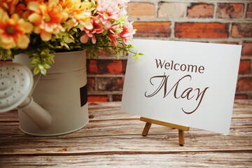 Welcome May text with flower bouquet decoration on wooden and old brick wall background