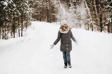 Walk through the winter forest. A girl in winter. The snow is flying. Catching snowflakes. Snowfall. Winter mood and smiles