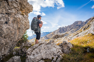 shot of a hiker with backpack from behind looking at rosengarten mountains 