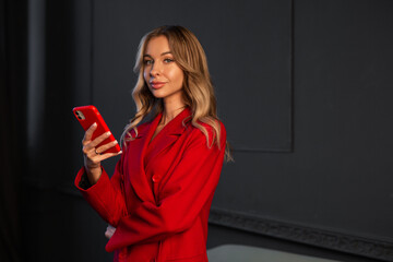 Naklejka premium beautiful caucasian businesswoman in a red suit with a phone 