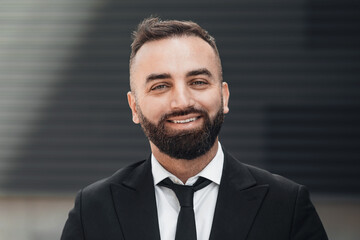 Successful business people. Happy middle-aged entrepreneur in suit standing in urban area and smiling at camera