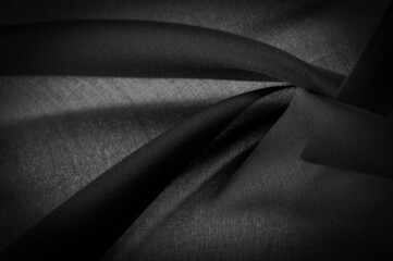 Background texture Dark black chiffon silk is a soft transparent fabric with a slight roughness (matte, creped) due to the use of twisted yarn.