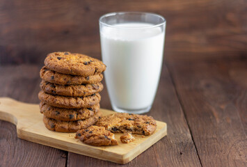 Oatmeal cookies with chocolate and a glass of milk on the old table.