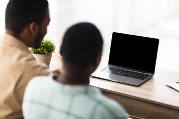 African Couple Video Calling Using Laptop With Blank Screen, Rear-View