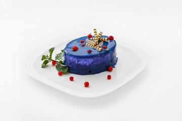 A piece of blue cake on a white plate with  berries for decoration - sweet dessert. Isolated